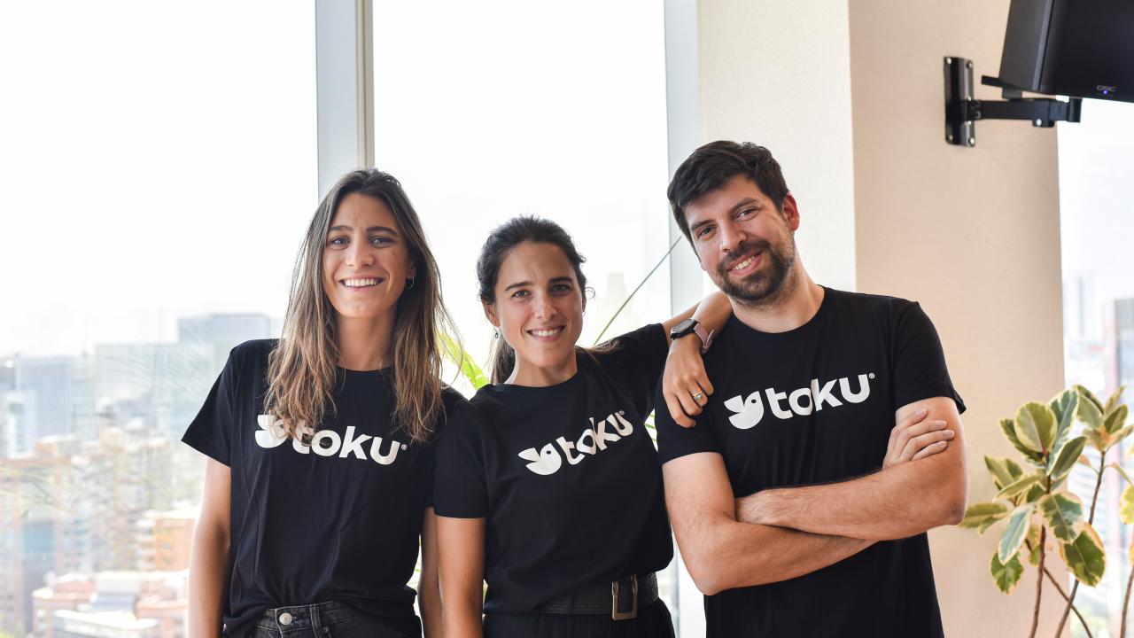 Tres personas posan juntas, sonriendo a la cámara en un ambiente informal.